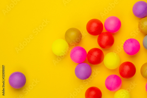 Abstract colored balls background. Multi-colored taw toy scattered on bright paper. Base for design nice backdrop, wallpaper, poster. Noisy surface texture