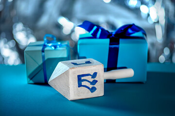 Dreidel, dreidle or dreidl with blue lettering on bright background. Gift box, spinning top, Jewish holiday of Hanukkah, Jewish teetotum