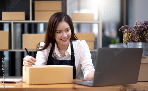 A female small business owner packing a customer's orders, writing a customer address