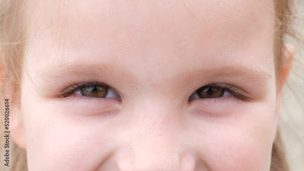 Beautiful brown eyes of small cheerful girl blinking and looking into camera with a happy sight. Portrait of cute face of young smiling child watching with positive emotion. Extremely close up Beautiful brown eyes of small cheerful girl blinking and looking into camera with a happy sight. Portrait of cute face of young smiling child watching with positive emotion. Extremely close up