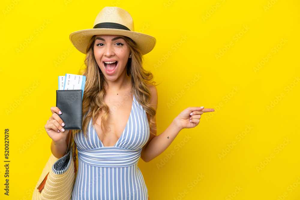 Young woman goes on vacation to the beach isolated on yellow background surprised and pointing finger to the side Young woman goes on vacation to the beach isolated on yellow background surprised and pointing finger to the side