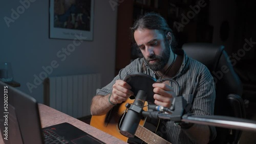 Young bearded songwriter adjusting his pop microphone filter before an online concert photo