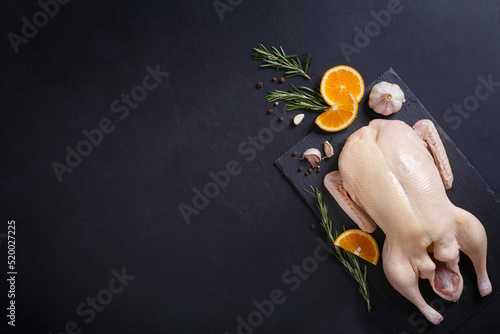 Print op canvas Raw and uncooked whole duck on slate board on black background