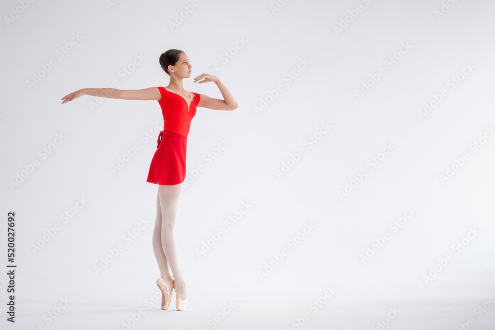 Beautiful young ballerina on a white background. The ballerina is dressed in a red leotard, pink leotards, pointe shoes.