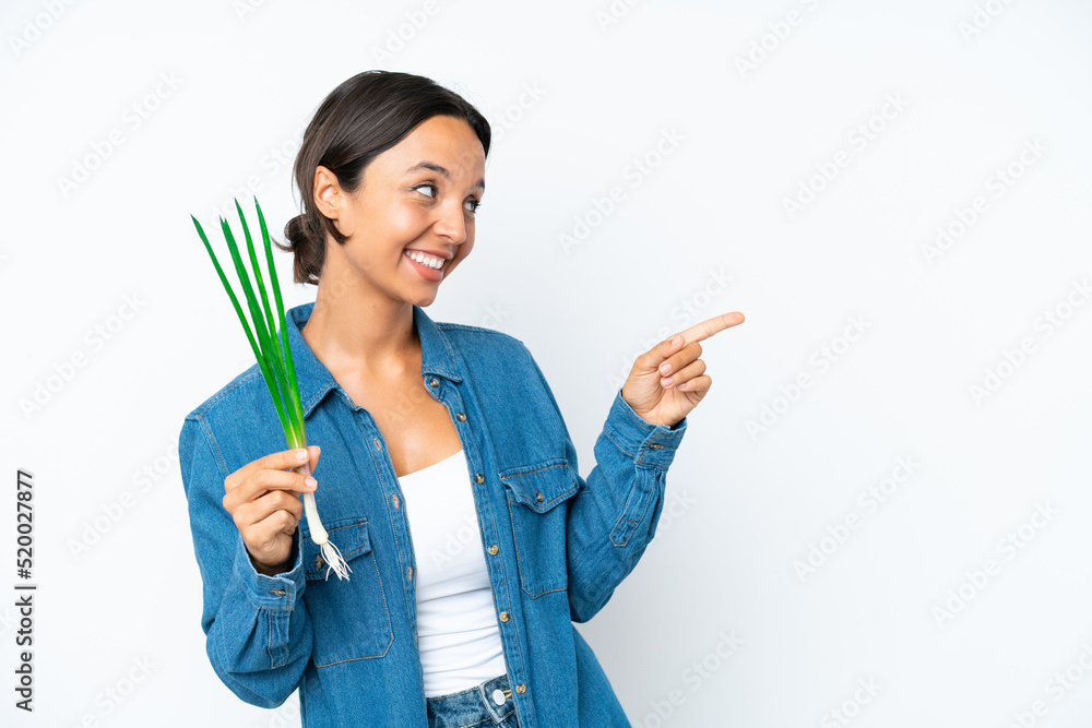 Young hispanic woman holding chive isolated on white background pointing finger to the side and presenting a product Young hispanic woman holding chive isolated on white background pointing finger to the side and presenting a product