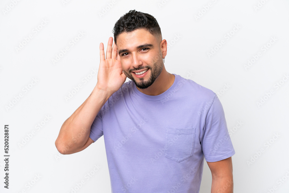 Fototapeta premium Young Arab handsome man isolated on white background listening to something by putting hand on the ear