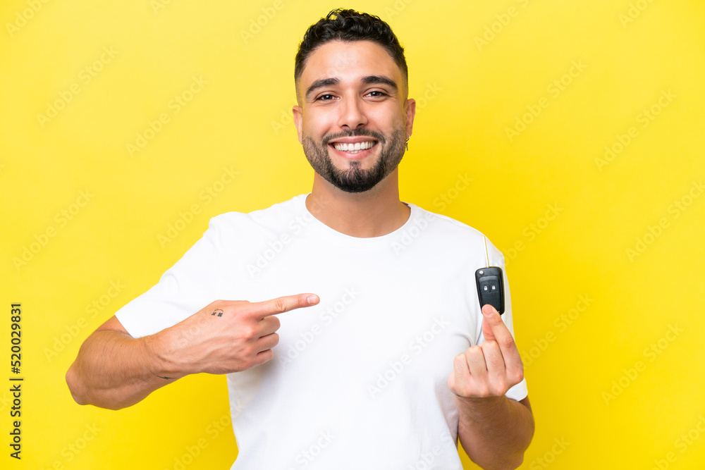 Young Arab man holding car keys isolated on yellow background with surprise facial expression Young Arab man holding car keys isolated on yellow background with surprise facial expression