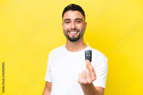 Young Arab man holding car keys isolated on yellow background with happy expression