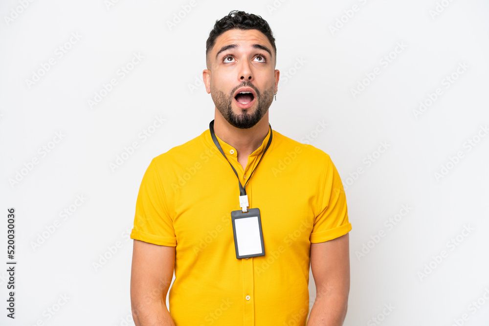 Young Arab man with ID card isolated on white background looking up and with surprised expression Young Arab man with ID card isolated on white background looking up and with surprised expression