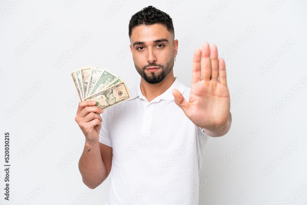 Young Arab man taking a lot of money isolated on white background making stop gesture Young Arab man taking a lot of money isolated on white background making stop gesture