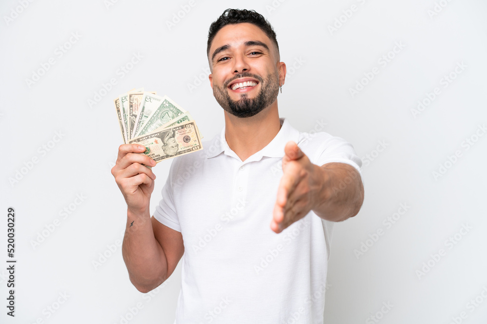Young Arab man taking a lot of money isolated on white background shaking hands for closing a good deal Young Arab man taking a lot of money isolated on white background shaking hands for closing a good deal