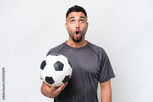 Arab young football player man isolated on white background looking up and with surprised expression
