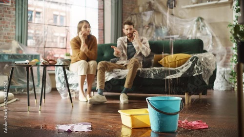 Roof is Leaking, Pipe Rupture at Home: Angry Couple Calling Insurance Company, Screaming into Phone in Frustration, Trying to Find Plumber, Master. Water Drips into Buckets in Living Room. Rack Focus