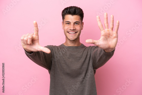 Young caucasian man isolated on pink background counting seven with fingers
