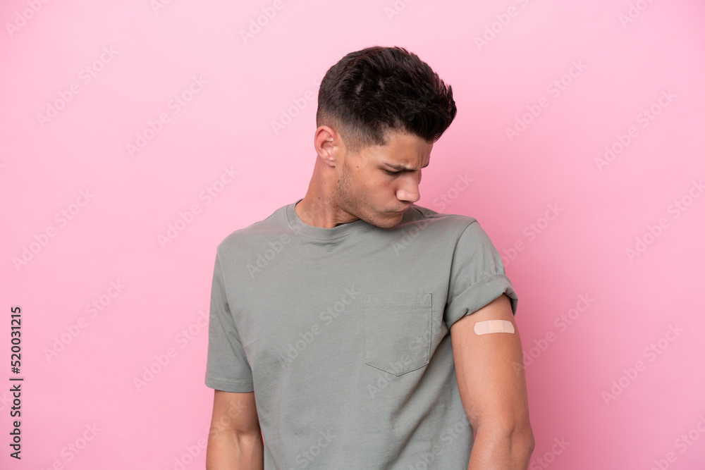 Young caucasian man wearing band-aids isolated on pink background with sad expression Young caucasian man wearing band-aids isolated on pink background with sad expression