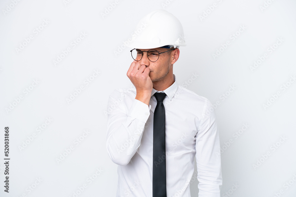 Young architect caucasian man with helmet and holding blueprints isolated on white background having doubts
