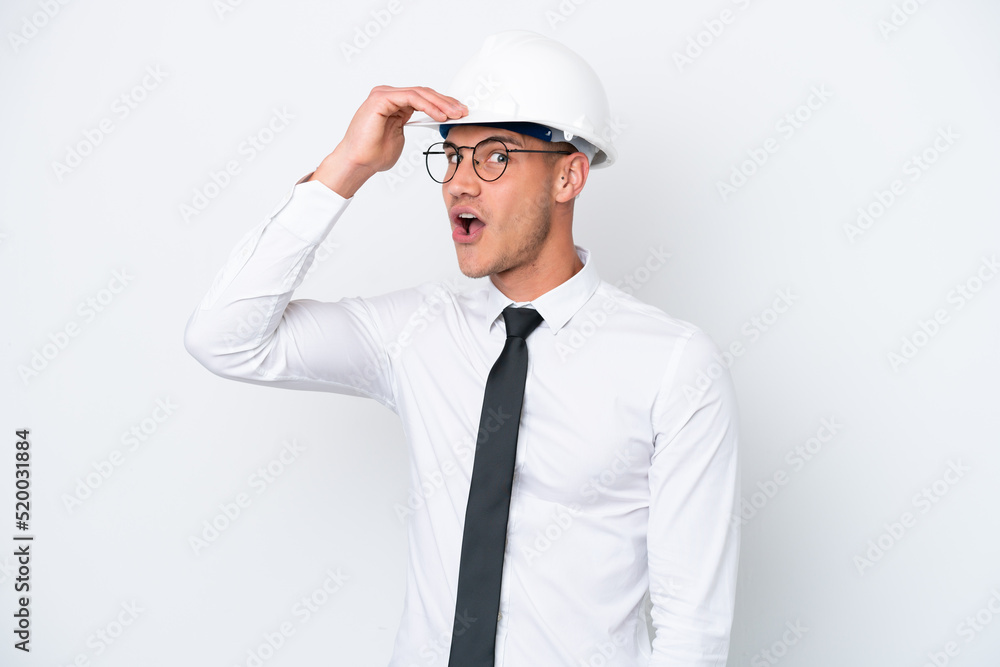 Young architect caucasian man with helmet and holding blueprints isolated on white background doing surprise gesture while looking to the side Young architect caucasian man with helmet and holding blueprints isolated on white background doing surprise gesture while looking to the side