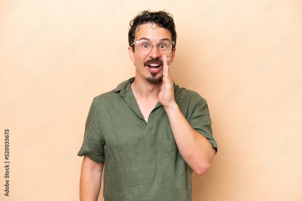 Young caucasian man isolated on beige background with surprise and shocked facial expression Young caucasian man isolated on beige background with surprise and shocked facial expression