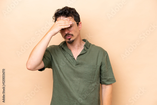 Young caucasian man isolated on beige background with headache © luismolinero