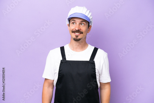 Fishmonger man wearing an apron isolated on purple background thinking an idea while looking up