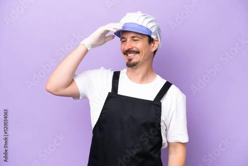 Fishmonger man wearing an apron isolated on purple background smiling a lot
