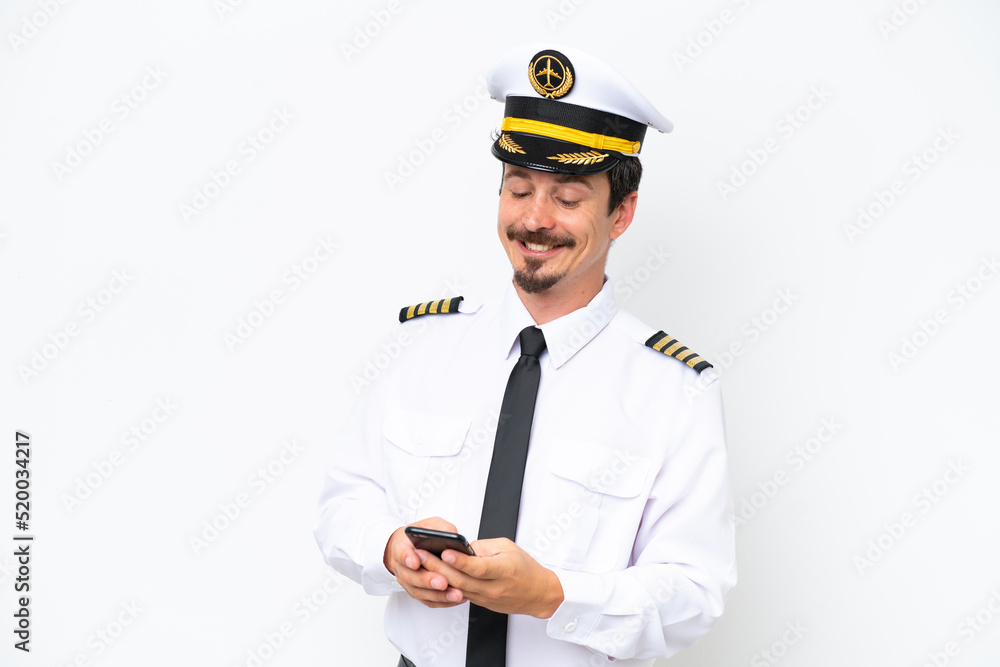Airplane caucasian pilot isolated on white background sending a message with the mobile Airplane caucasian pilot isolated on white background sending a message with the mobile