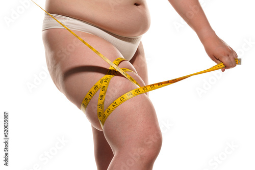 Overweight woman with tape is measuring fat on legs photo