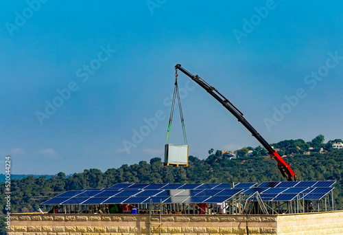 Installation of solar cell electric panels on a roof of multi-storey building in Israel. Solar panels on the house roof. Workers are installing the solar cell farm power plant. eco technology.