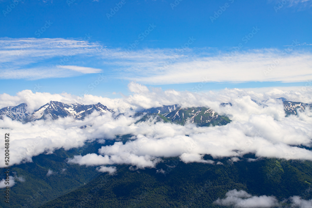 mountain landscape with blue sky above clouds, hilltops and natural green forests, trekking and hiking,travel and tourism,