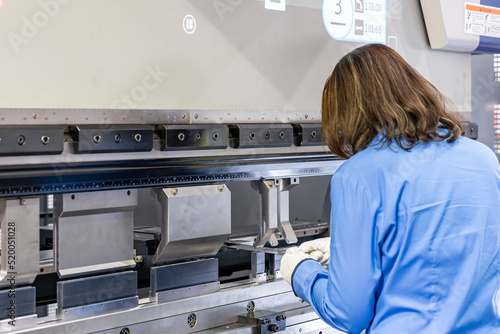 Wallpaper Mural Close up technician hand hold metal flat sheet insert between punch and v die of the semi automatic cnc hydraulic press brake or bending machine  during folding forming. Torontodigital.ca