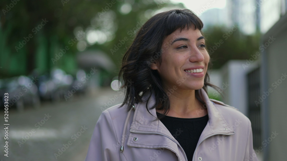 Happy young woman walking outside. One confident hispanic Brazilian girl walks outdoors in street smiling Happy young woman walking outside. One confident hispanic Brazilian girl walks outdoors in street smiling