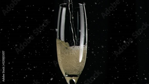Animation of white spots over glass of champagne on black background photo