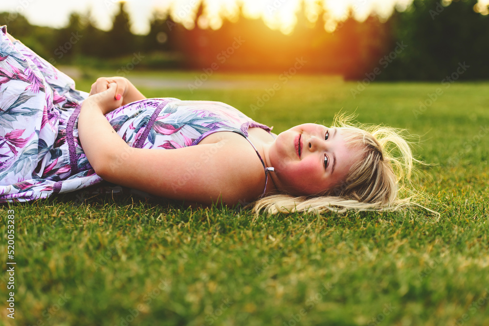 Trisomy 21 child having fun outside in summer season lay in the ground Trisomy 21 child having fun outside in summer season lay in the ground