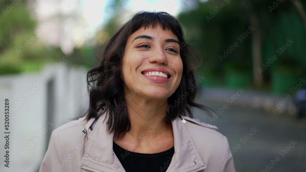 Smiling happy young woman walking outside. Portrait face of one hispanic latina girl walks smiling