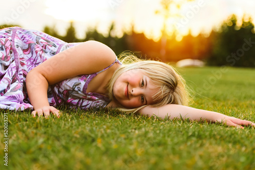 Trisomy 21 child having fun outside in summer season lay in the ground