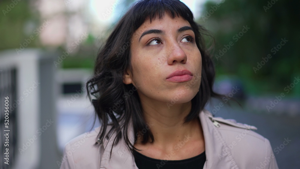 Pensive young woman walking outside in street. One thoughtful hispanic latin person walks in contemplation Pensive young woman walking outside in street. One thoughtful hispanic latin person walks in contemplation