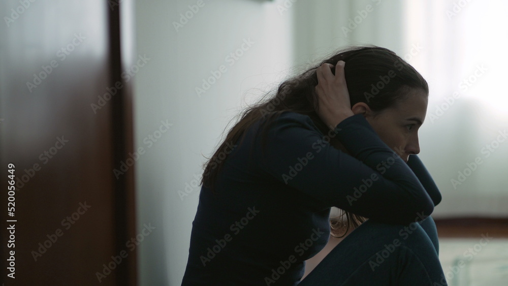 Anxious woman sitting on floor suffering from mental illness at home. Lonely person feeling despair and hopelessness