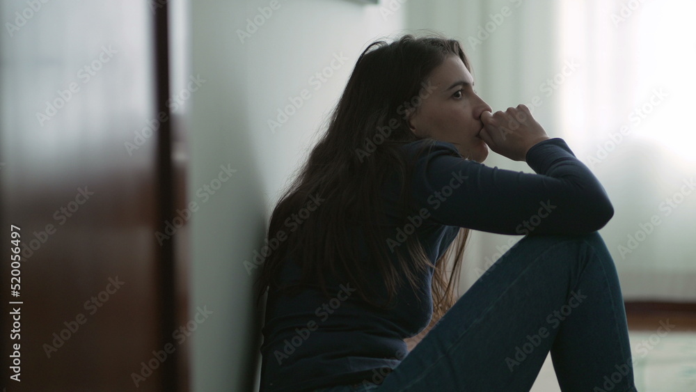 Anxious woman sitting on floor suffering from mental illness at home. Lonely person feeling despair and hopelessness Anxious woman sitting on floor suffering from mental illness at home. Lonely person feeling despair and hopelessness