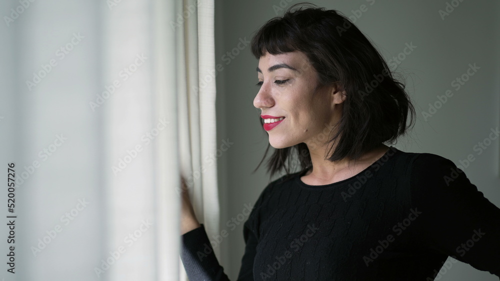 One beautiful hispanic girl looking out through curtain window checking sunlight day