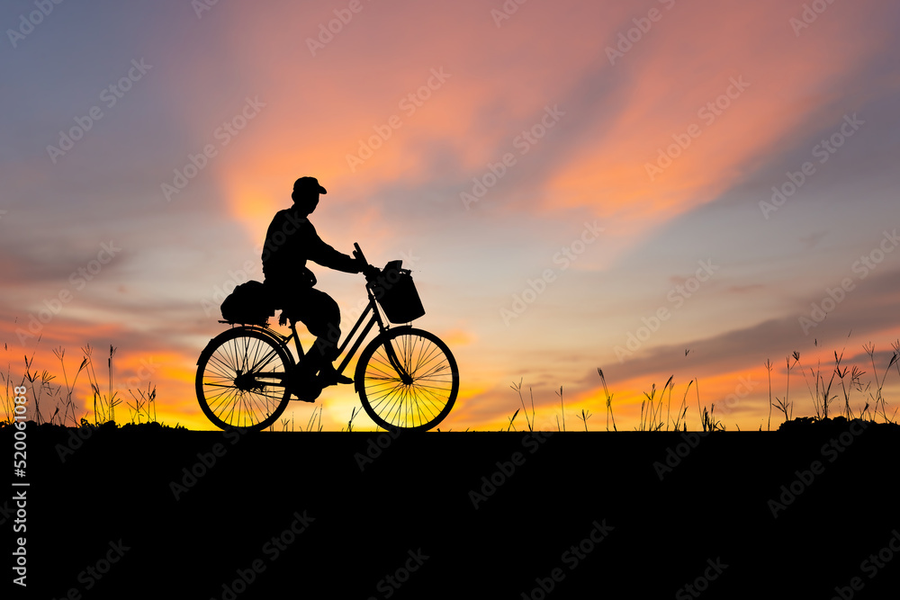 Fototapeta premium Silhouette of Senior Asian man riding a bicycle at sunset in evening time