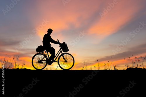 Silhouette of Senior Asian man riding a bicycle at sunset in evening time
