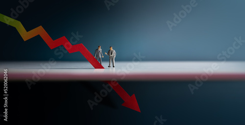 Recession, Inflation and Depression Concepts. Economic Crisis. Graph Fall Down, Business Collapse. Two Miniature Figure of Businessman Looking at a Red Graph Arrow Down photo