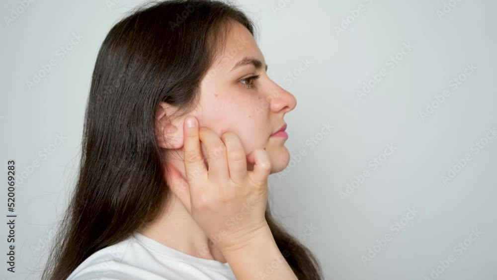 A woman with temporomandibular joint dysfunction massages the masticatory muscles. A woman with temporomandibular joint dysfunction massages the masticatory muscles.