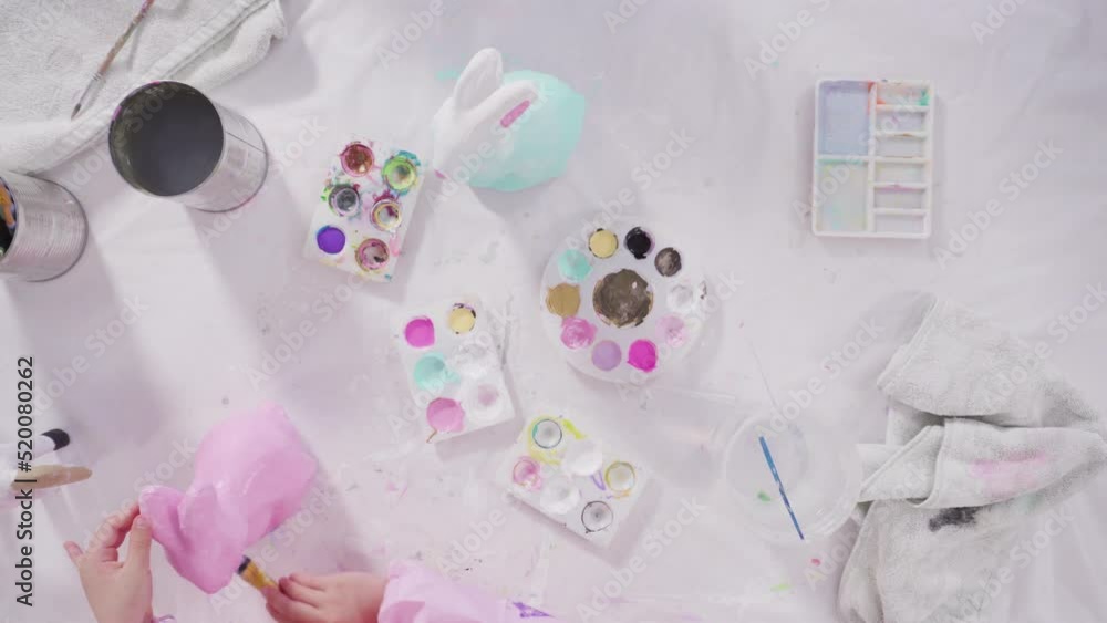 Flat lay. Little girl painting paper mache figurines with acrylic paint for her homeschooling art project. Flat lay. Little girl painting paper mache figurines with acrylic paint for her homeschooling art project.