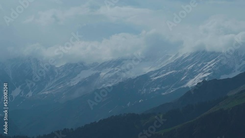 Dark stormy clouds on snow covered Himalayan mountains during monsoon as seen from Manali, Himachal Pradesh, India. Clouds cover the peak of the mountains during the stormy weather in monsoon. photo