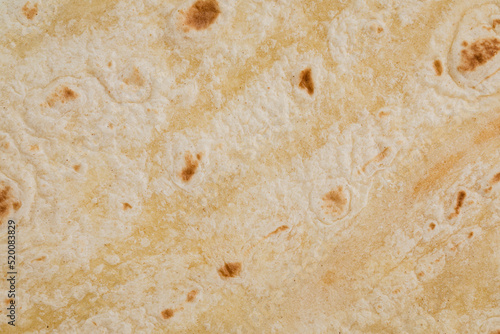 Plain wheat tortilla wraps. Spanish or Mexican circular unleavened flatbread from wheat flour. Ingredient for cooking fast food or snack. Closeup, texture background photo