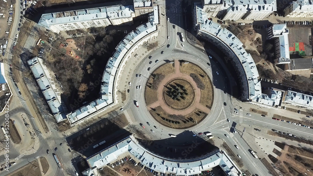 Top view of roundabout in city center. Roundabout with busy traffic of cars, surrounded by houses in city center on sunny day