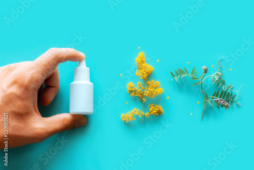 Bild auf Leinwand nasal spray in hand next to flowering plants on blue background stop allergy