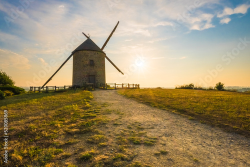 An old traditional windmill in the field at sunset in Pontorson, Normandy, France