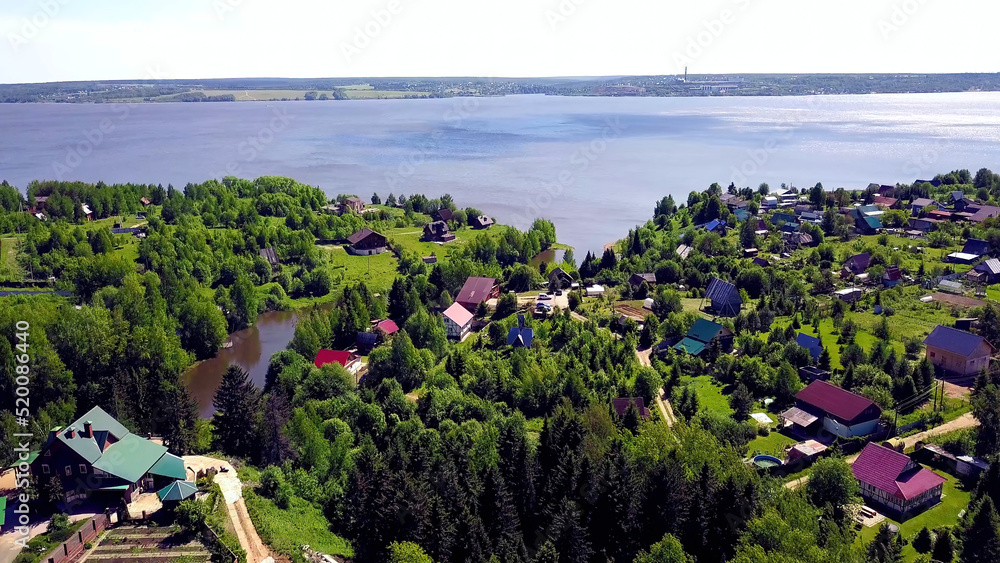 Cottage town on background blue lake. Clip. Top view of a country village in a forest area by the lake
